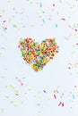 Colored sugar sprinkles are collected in the shape of a heart isolated on a white background Royalty Free Stock Photo