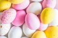 Colored sweet little eggs. Multi-colored Easter eggs on a plate. Sweet Easter eggs shot close up. Festive chocolate eggs in pink,