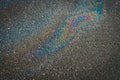 Colored texture of oil products on asphalt in bright sunlight after rain.