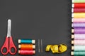 Colored thread coils, scissors, needles and a tailor meter on a black background Royalty Free Stock Photo