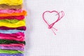 Colored thread for embroidery on white canvas, a needle with red thread in the shape of a heart. The concept of love for a hobby. Royalty Free Stock Photo