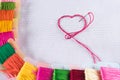 Colored thread for embroidery on white canvas, a needle with red thread in the shape of a heart. The concept of love for a hobby. Royalty Free Stock Photo