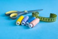Colored thread for sewing. Threads into a reel roulette, and scissors against a blue background Royalty Free Stock Photo