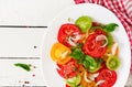 Colored tomato salad with onion and basil pesto.