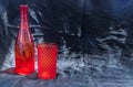 Colored transparent red glass cup and red glass bottle for water drinking and surface reflections on a black background Royalty Free Stock Photo
