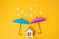 Colored umbrellas on a yellow background and paper raindrops. Conceptuality and place for the text