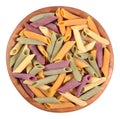 Colored uncooked italian pasta penne in a wooden bowl on a white Royalty Free Stock Photo