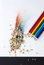 Colored watercolor pencils of rainbow colors and shavings from them after sharpening on a white background. Royalty Free Stock Photo
