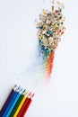 Colored watercolor pencils of rainbow colors and shavings from them after sharpening on a white background. Royalty Free Stock Photo