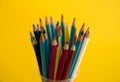 Colored wooden pencils for drawing in a glass stand on a white background. Children`s multi-colored pencils for drawing