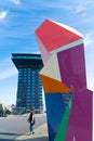 Colorful abstract sculpture named Marathonbeeld in street with tourist on street and high-rise modernist building behind. in