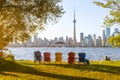 Colorful adirondack chairs on Toronto Island Park at sunset time. Toronto City downtown skyline in the background. Royalty Free Stock Photo