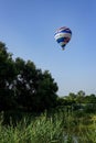 Colorful air balloon flies over the city suburbs.