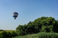 Colorful air balloon flies over the city suburbs.