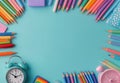 Colorful arrangement of pencils and clock on a turquoise background for creative projects Royalty Free Stock Photo