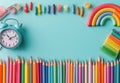 Colorful arrangement of pencils and clock on a turquoise background for creative projects Royalty Free Stock Photo