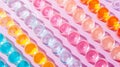 A colorful array of gel beads arranged neatly in rows on a vibrant pink background
