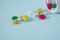 Colorful, assorted pharmaceutical medicine pills poured out of the bottle. many pills and tablets isolated on blue