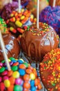 Colorful Assortment of Candy Apples Covered in Chocolate, Caramel, and Sprinkles at a Festive Fairground Treat Stand