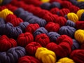 A colorful assortment of yarn balls in red, yellow, and purple hues, neatly stacked together