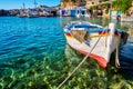 Colorful authentic Greek fishing boat anchored in small village in crystal clear waters. Whitewashed boat garages, blue