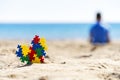 Colorful autism awareness heart on the sand and back view to silhouette of the child sitting on the beach and looking to