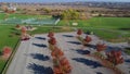 Colorful autumn leaves in empty parking lot near playground, tennis courts and farm prairie plateau with silos background in Royalty Free Stock Photo