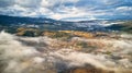 Colorful autumn morning over foggy mountain valley. Village covered by low clouds. Fall rural landscape. Misty cold November Royalty Free Stock Photo