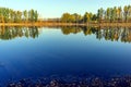 Colorful autumn trees near the river. Blue sky reflected in calm water. Landscape in sunny day Royalty Free Stock Photo