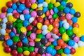 Colorful background of multicolored candy dragees. Round  scattered sweets on a yellow bright background. Happy multicolor texture Royalty Free Stock Photo