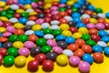 Colorful background of multicolored candy dragees. Round  scattered sweets on a yellow bright background. Happy multicolor texture Royalty Free Stock Photo