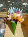 Colorful Balinese offering with roses and hydrangeas in a palm leaf cone, placed in a woven basket under sunlight. Royalty Free Stock Photo