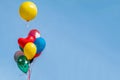 Colorful balloon floating in mid air against a bright blue sky. Royalty Free Stock Photo