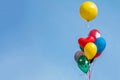 Colorful balloon floating in mid air against a bright blue sky. Royalty Free Stock Photo