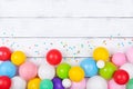 Colorful balloons and confetti on white table top view. Festive or party background. Flat lay. Birthday greeting card