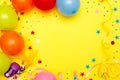 Colorful balloons and confetti on yellow table top view. Festive or party background. Flat lay style. Birthday greeting card. Royalty Free Stock Photo