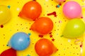 Colorful balloons and confetti on yellow table top view. Festive or party background. Flat lay style. Birthday greeting card. Royalty Free Stock Photo