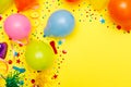 Colorful balloons and confetti on yellow table top view. Festive or party background. Flat lay style. Birthday greeting card. Royalty Free Stock Photo