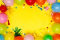 Colorful balloons and confetti on yellow table top view. Festive or party background. Flat lay style. Birthday greeting card. Royalty Free Stock Photo