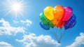 Colorful balloons float in a bright blue sky with puffy white clouds and a bright sun Royalty Free Stock Photo