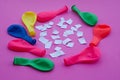 Colorful balloons and small pieces of paper on pink background.