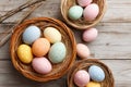 Colorful baskets filled with decorated eggs placed on a rustic wooden table for Easter celebration. Royalty Free Stock Photo