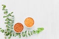 Colorful bath salt in small bowl and eucaliptus branch on white background. Top view, copy space. SPA and healthcare concept