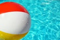 Colorful beach ball in swimming pool on sunny day. Space for text Royalty Free Stock Photo