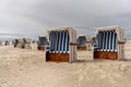 Colorful beach baskets on an idyllic golden sand beach on the German Wadden Sea coast under an expressive sky