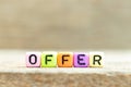 Colorful bead with letter in word offer on wood background