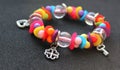 Colorful beads and silver charms of wrist bracelet isolated on black angle view