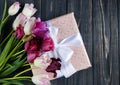 Colorful beautiful pink violet tulips and gift box on gray wooden table. Valentines, spring background. floral mock up Royalty Free Stock Photo