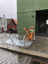 Colorful bicycle parked down town. Nice and orange with flower decoration.