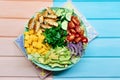 Colorful big paleo salad bowl with frilled chicken meat and fresh vegetables and fruits on colored wooden background Royalty Free Stock Photo